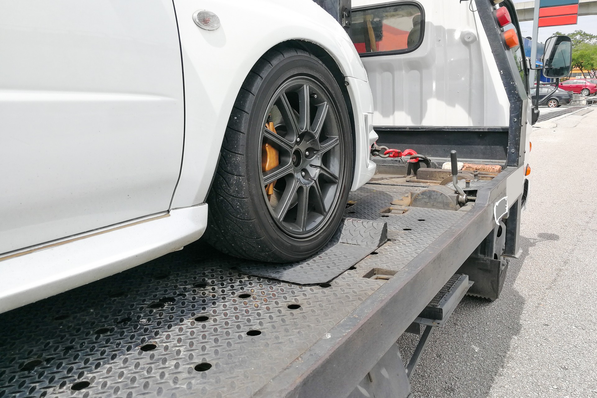 Car towed onto flatbed tow truck with hook and chain